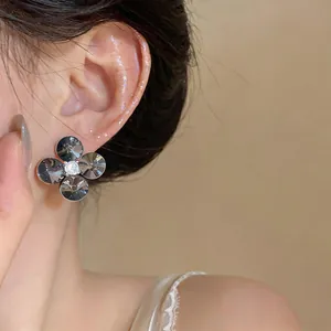 Close-up of elegant four-petal flower stud earring with dark grey faceted stones