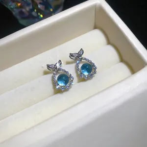 Elegant sea blue zircon fish tail stud earrings displayed in a luxury beige jewelry box