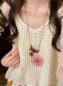 Detailed view of handmade pink preserved flower necklace with wooden beads on leather cord