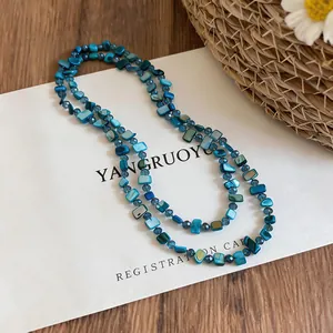 Close-up of a double-layered blue shell bead necklace in a coastal-themed aesthetic setting.