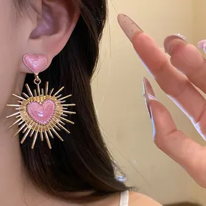 Gros plan de boucles d'oreilles vintage cœur rose avec un design de soleil doré élégant