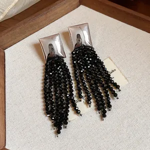 Gros plan détaillé de longs pompons en perles de verre noires sur des boucles argentées