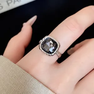 Macro detail of a silver ring featuring a dark grey square faceted gemstone.