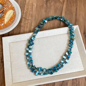 Detailed macro shot of blue square shell beads on a double-layered necklace strand