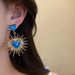 Gros plan de boucles d'oreilles cœur en émail bleu vintage avec des détails dorés