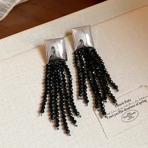 Gros plan d'élégantes boucles d'oreilles carrées en argent avec glands de perles.