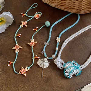 Detailed view of colorful beaded necklaces with sea-themed pendants like fish and shells.