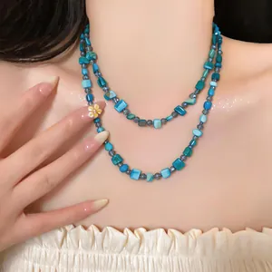 Detailed macro view of a layered necklace featuring blue square shell beads and crystals