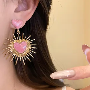 Gros plan de boucles d'oreilles vintage en forme de cœur rose à paillettes dorées.