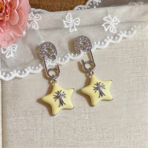 Detail shot of elegant silver safety pin earrings with zirconia and yellow star charms