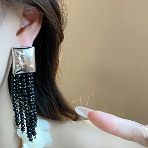 Gros plan de boucles d'oreilles carrées avec glands en perles de verre noires.