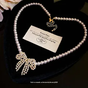 Elegante 18 Karat vergoldete Perlenkette mit schimmerndem Zirkonia-Bogenanhänger.