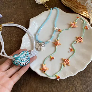 Detailed close-up of three summer style handmade beaded necklaces with fish and shell charms