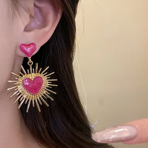 Détail de boucles d'oreilles vintage avec cœur rose scintillant et beaux rayons dorés