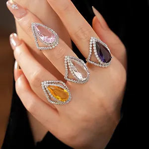 Close-up of four pear-cut zircon open rings in assorted colors on a hand