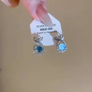 Close-up of elegant S925 silver fish tail earrings with sea blue zircon stones