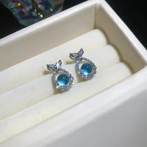 Detailed view of elegant sea blue zircon stud earrings with sparkling fish tail design.