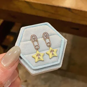Detail view of silver zircon paperclip star stud earrings placed in a light blue jewelry box