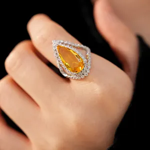 Detailed view of elegant yellow pear-shaped zircon ring with halo crystals on hand