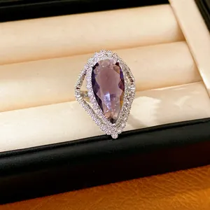 Detail of a luxury pear-shaped purple zircon ring with a sparkling halo in a jewelry box.