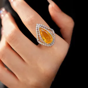 Detailed close-up of a vintage-style pear-cut orange zircon ring with white stone halo