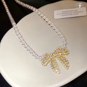 Detailansicht einer eleganten, 18 Karat vergoldeten Zirkon-Schleifenkette mit Perlen