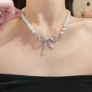 Detailansicht einer 18k vergoldeten Perlenkette mit einem silbernen Schleifenanhänger.