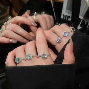 Close-up detail of sparkling round zircon rings in vibrant candy colors on fingers.