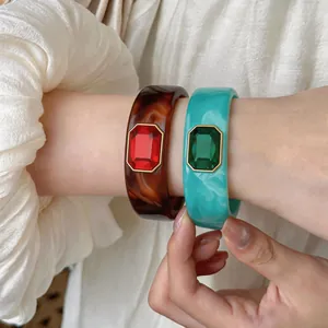 Gedetailleerde close-up van vintage hars armbanden met rechthoekige rode en groene stenen.