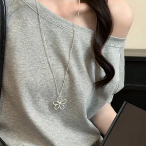 Collier avec pendentif fleur en perles argentées porté sur un haut gris élégant