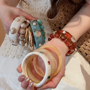 Detailed view of European style resin bangle set with shell and pearl embellishments