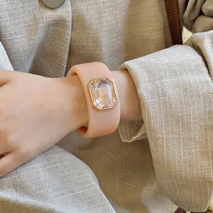 Close-up van een nude hars armband met een groot kristal in smaragdgeslepen goudkleurig.