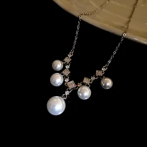 Gros plan détaillé d'un collier de perles avec des breloques carrées serties de zircons.