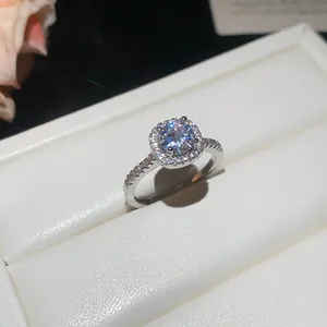 Detailed close-up of a sparkling round zircon ring set on a white jewelry cushion.