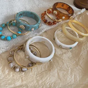 Macro view of assorted resin bangles and bead bracelet sets on rustic textured paper background