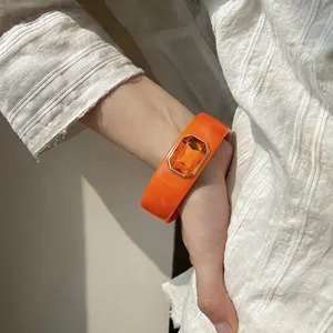 Macrodetail van een oranje harsarmband met een grote rechthoekige oranje edelsteen