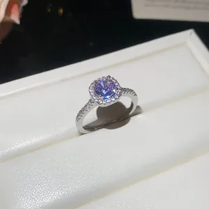Macro view of a silver ring with a round purple zircon stone set in a white jewelry box.