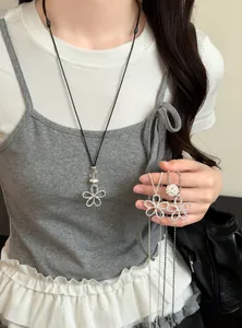Détail d'un collier fleur en argent avec perles sur mannequin et dans la main.