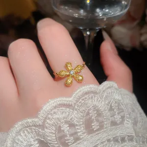 Primo piano di un anello a fiore dorato con zirconi gialli e trasparenti al dito