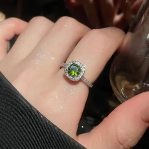 Detailed close-up of a silver ring with a sparkling green round zircon and halo stones