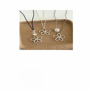 Détail de trois colliers fleurs argentés de style coréen avec perles sur un plateau rustique