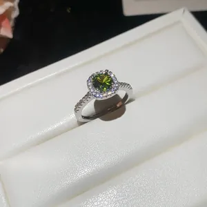 Close-up detail of a classic silver halo ring featuring a brilliant green round zircon