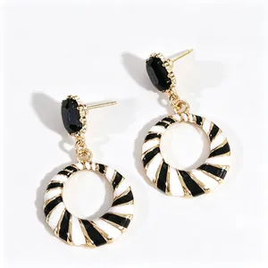 Modern black and white striped hoop earrings with faceted black stones and gold base.