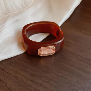 Detail van een amberkleurige vierkante harsarmband met een luxe rechthoekig kristal