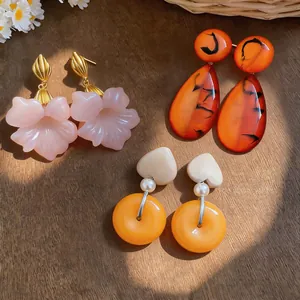 Close-up view of vintage French resin earrings in flower, heart, and teardrop shapes.