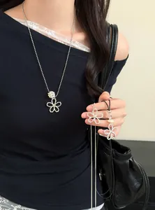 Collier style coréen argenté avec perle et pendentif fleur en cristal sur un haut noir.
