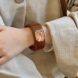 Detailweergave van een brede bruine hars armband met een groot champagnekleurig kristal