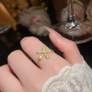 Primo piano di un anello a fiore placcato oro con zirconi indossato su una mano