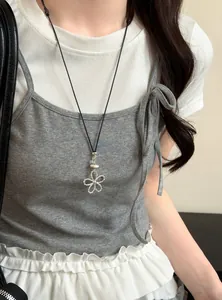 Vue détaillée d'un collier pendentif fleur creuse en argent porté avec une tenue décontractée