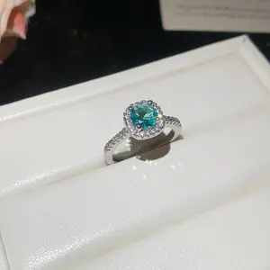 Detailed view of an elegant ring featuring a teal gemstone and sparkling zircon halo